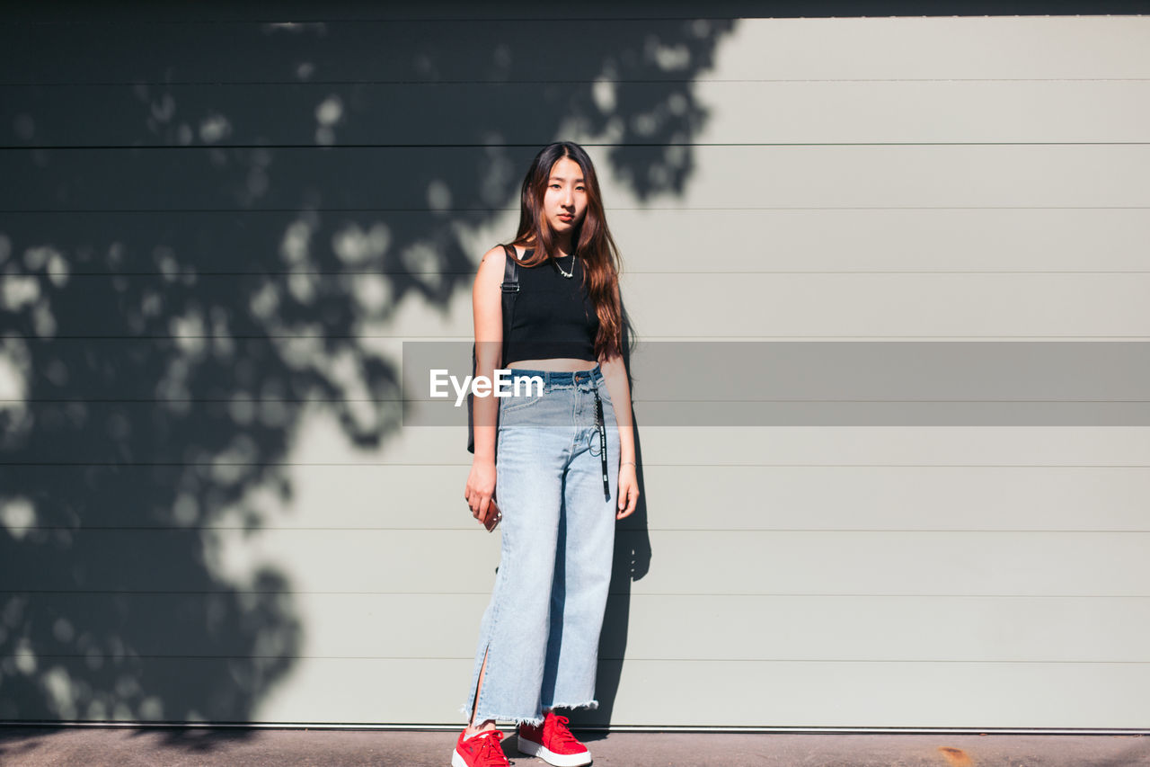 Portrait of woman standing against wall