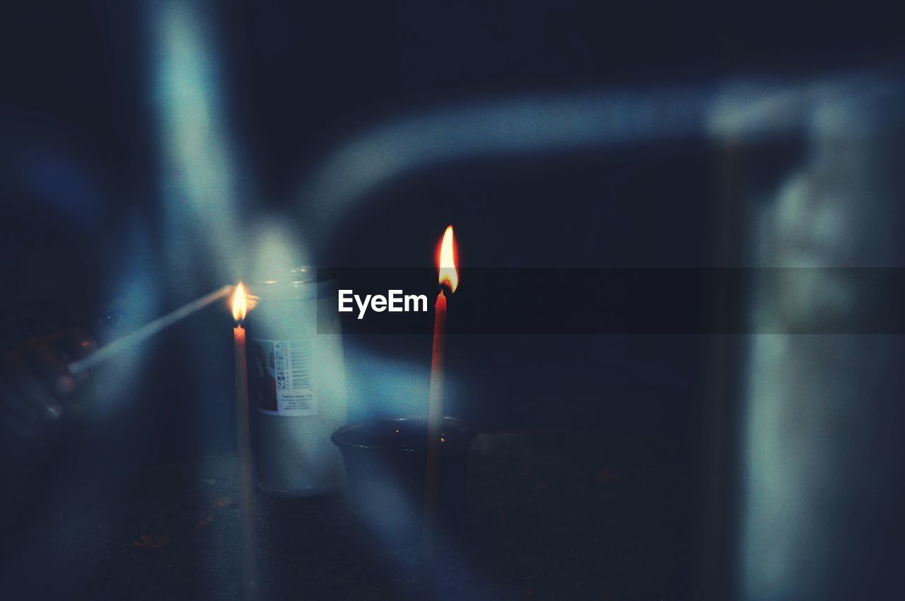 Close-up of person burning candle in darkroom