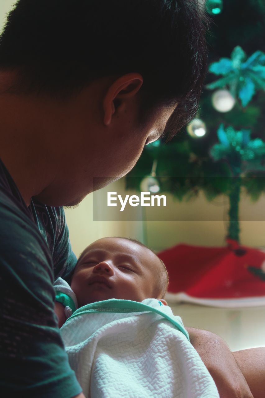 Father holding baby while sitting at home