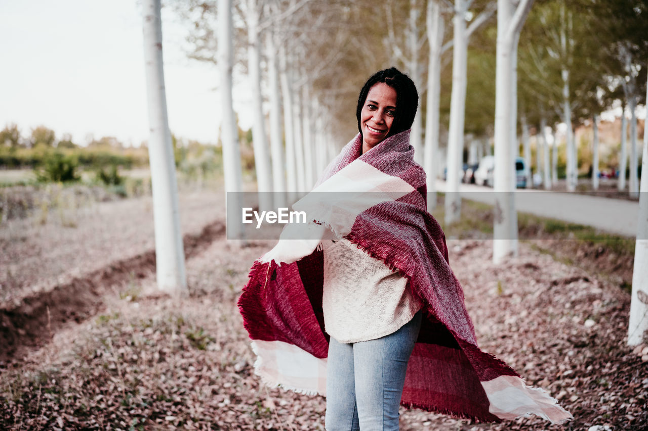 Portrait of smiling woman standing amidst trees