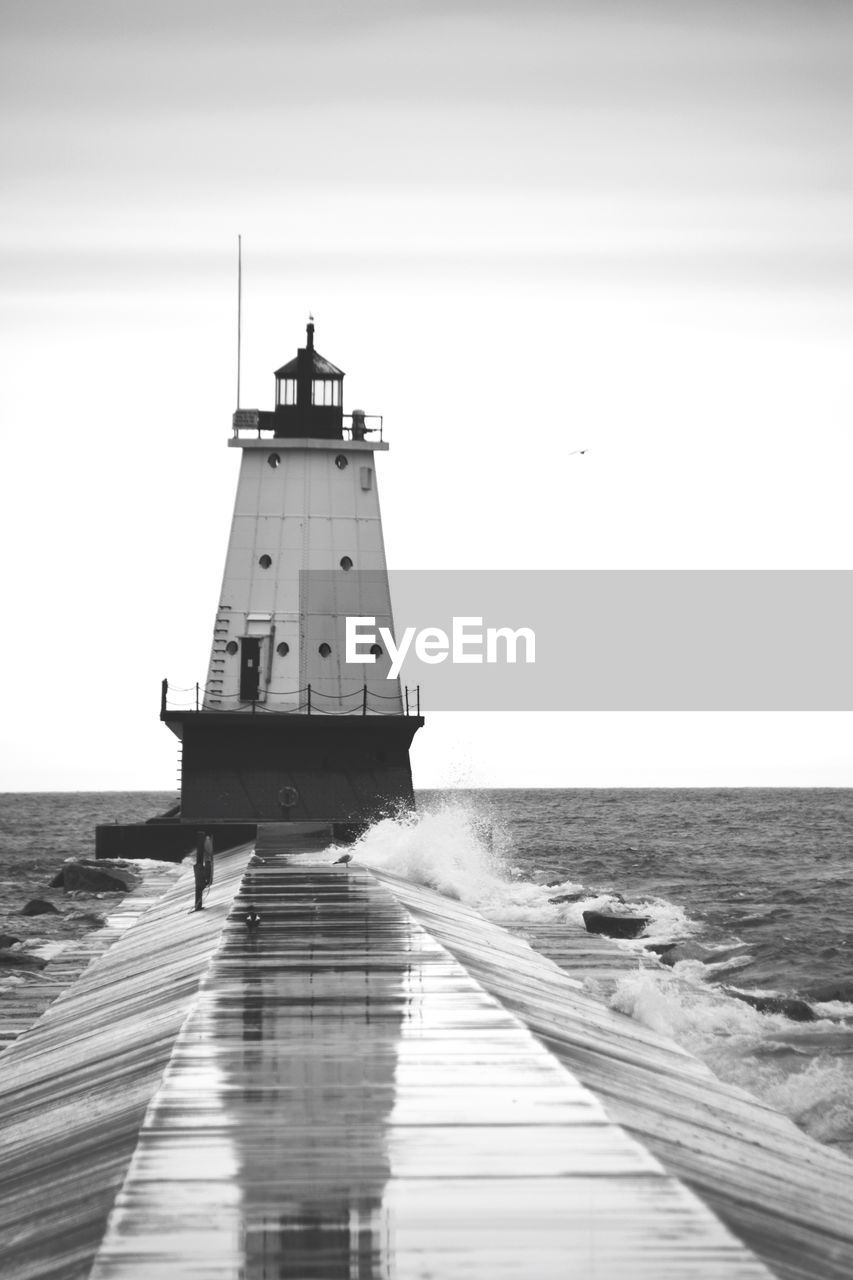 Lighthouse by sea against sky