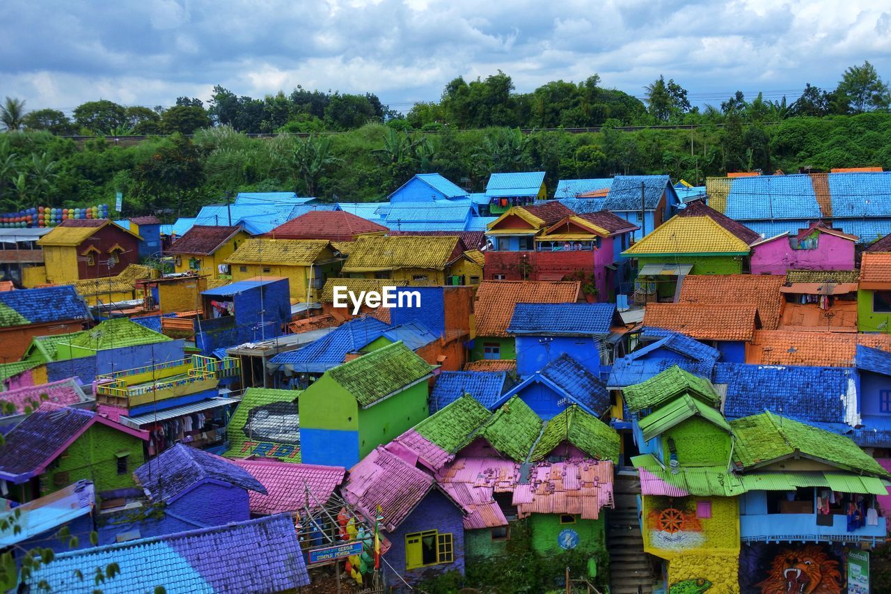High angle view of multi colored houses by building against sky