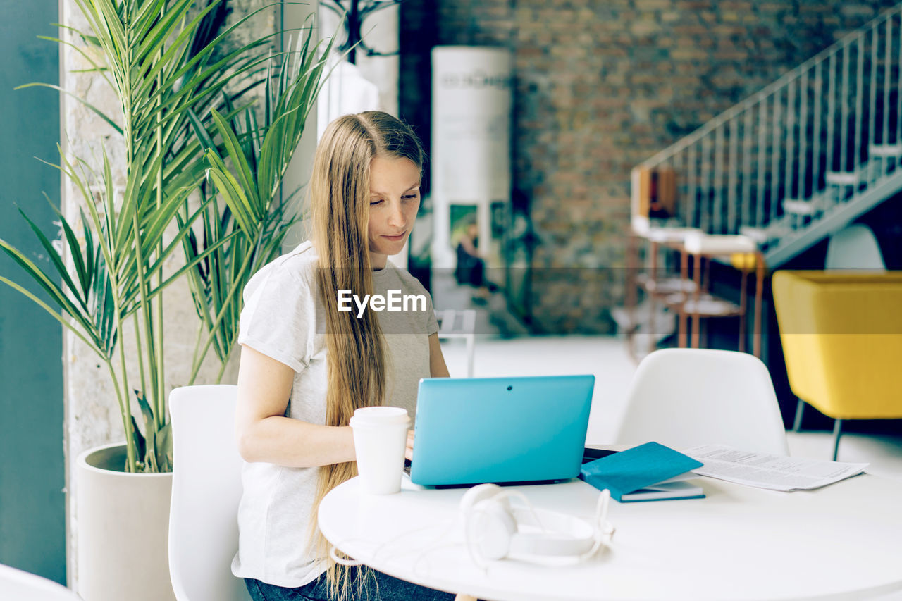 Young woman working on a laptop in a cafe at a table. businesswoman, freelancer, remote work.