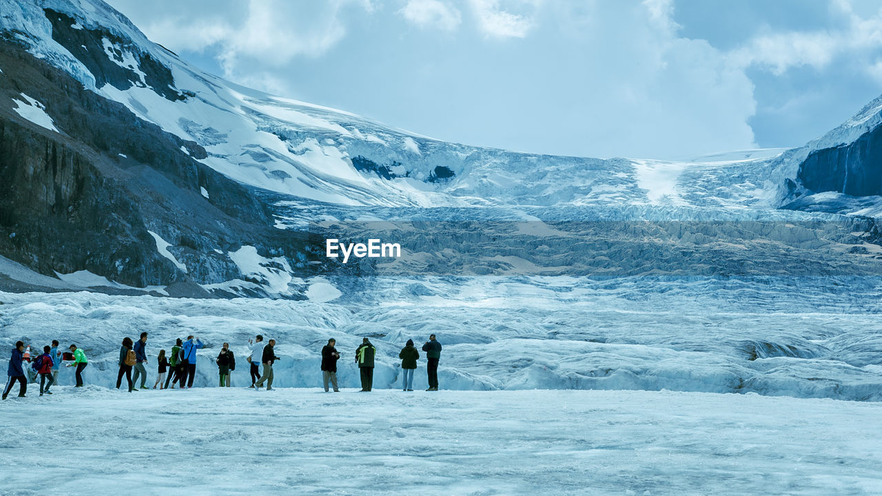 GROUP OF PEOPLE ON SNOWCAPPED MOUNTAINS AGAINST SKY