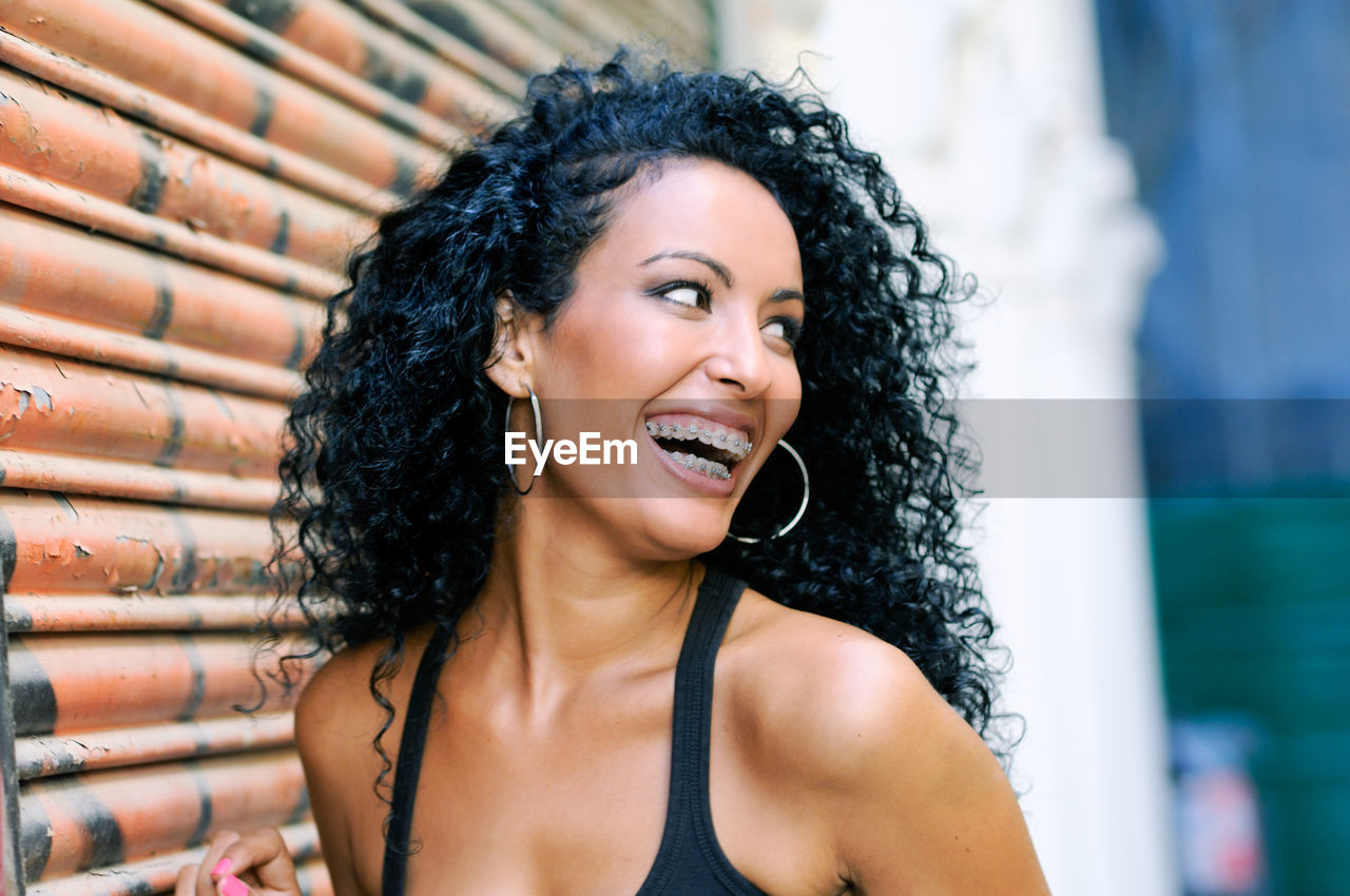 Close-up smiling young woman with braces standing by shutter