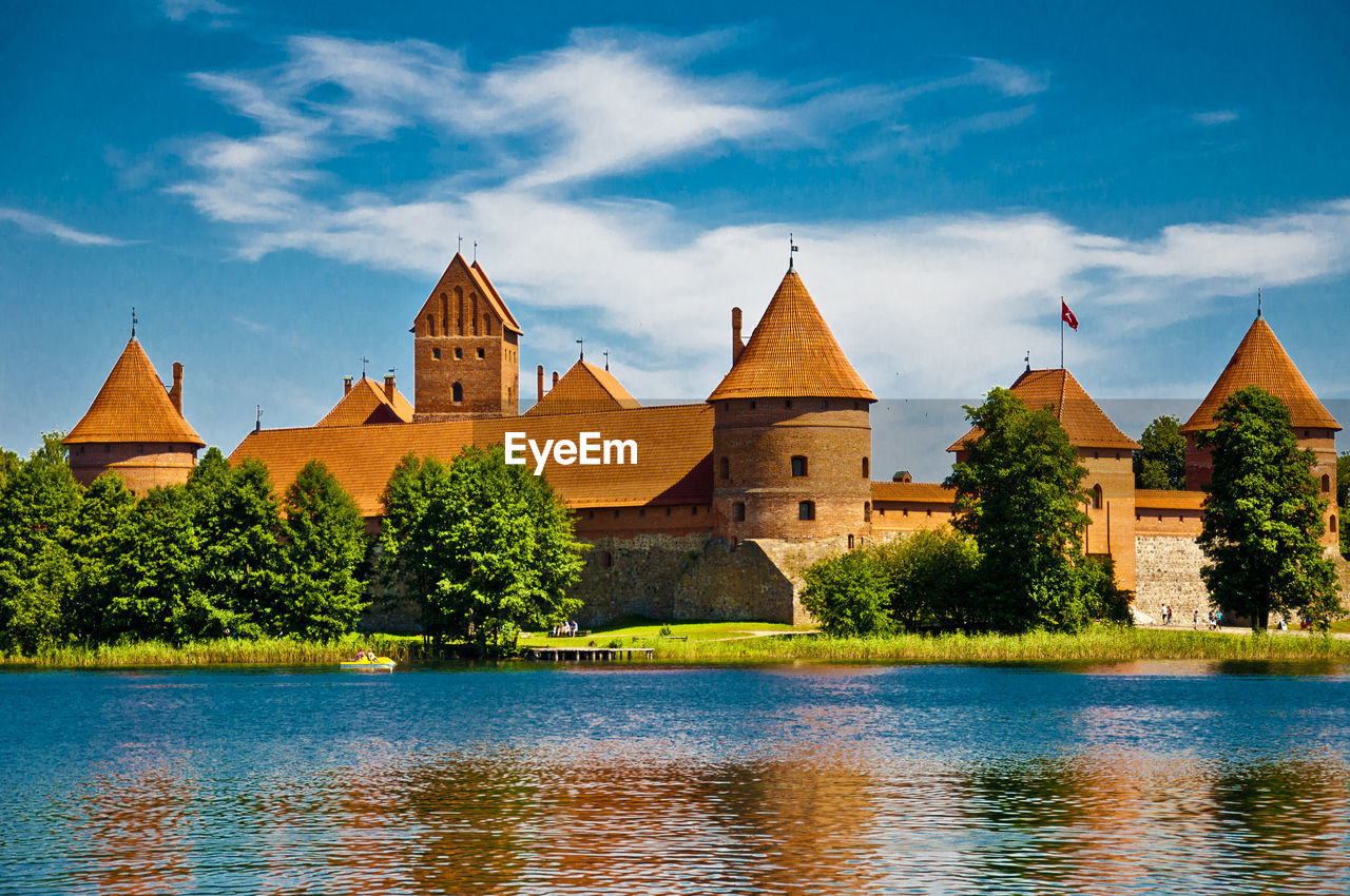 Old castle by river against sky