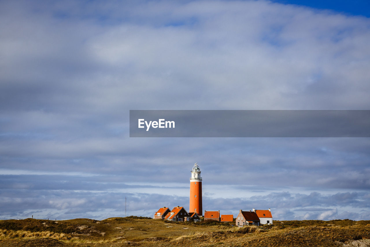 Lighthouse on field against sky