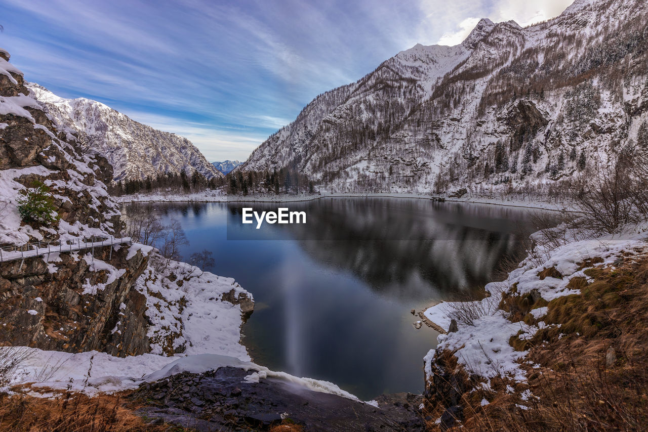 Scenic view of lake by snowcapped mountains against sky