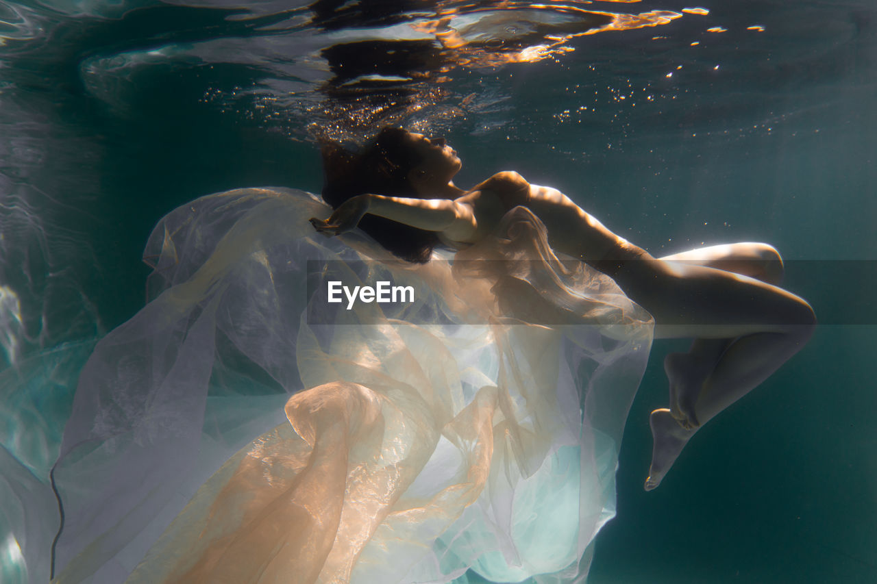 Woman with curtain swimming in pool