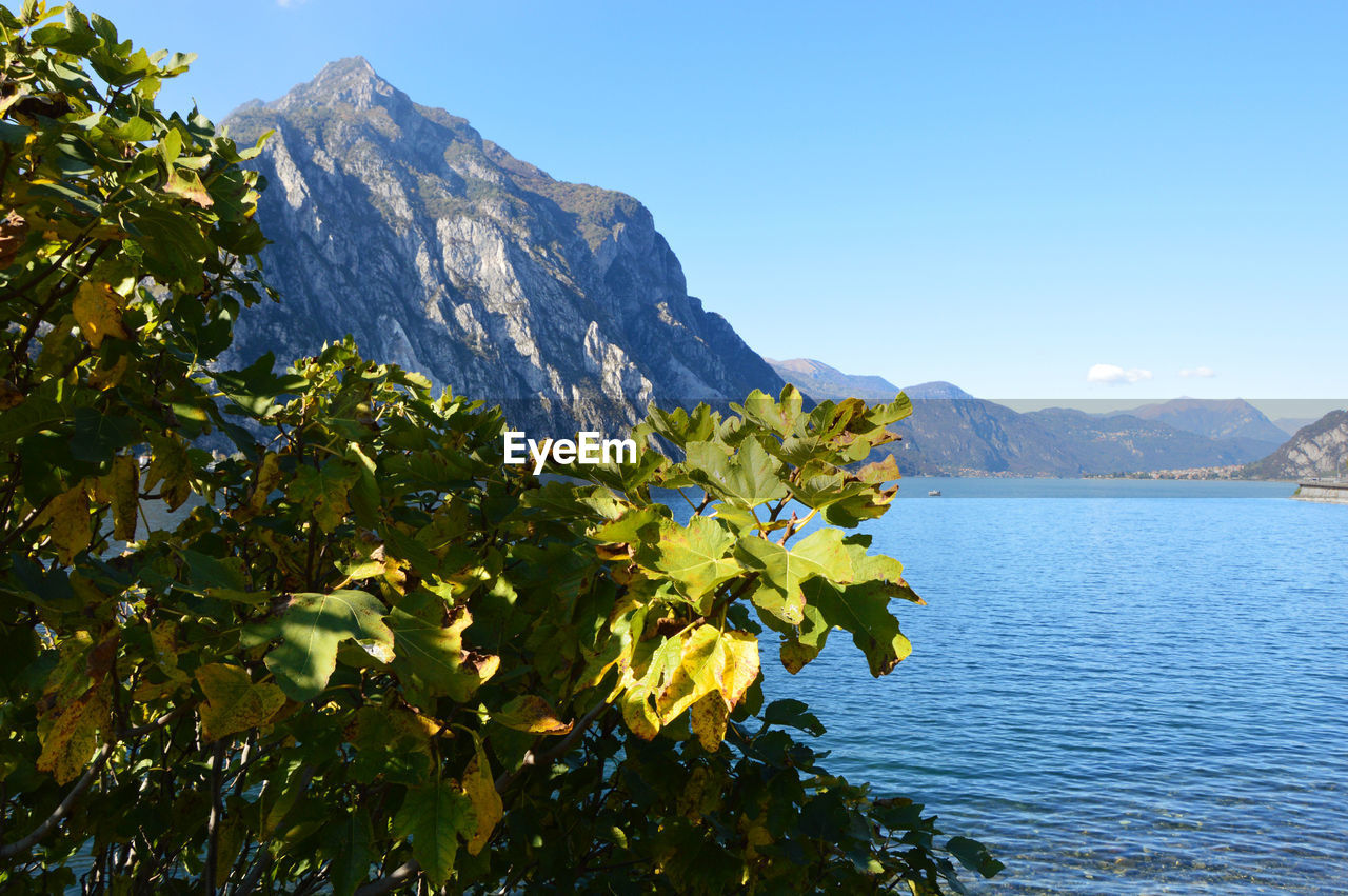 Scenic view of sea and mountains against clear blue sky