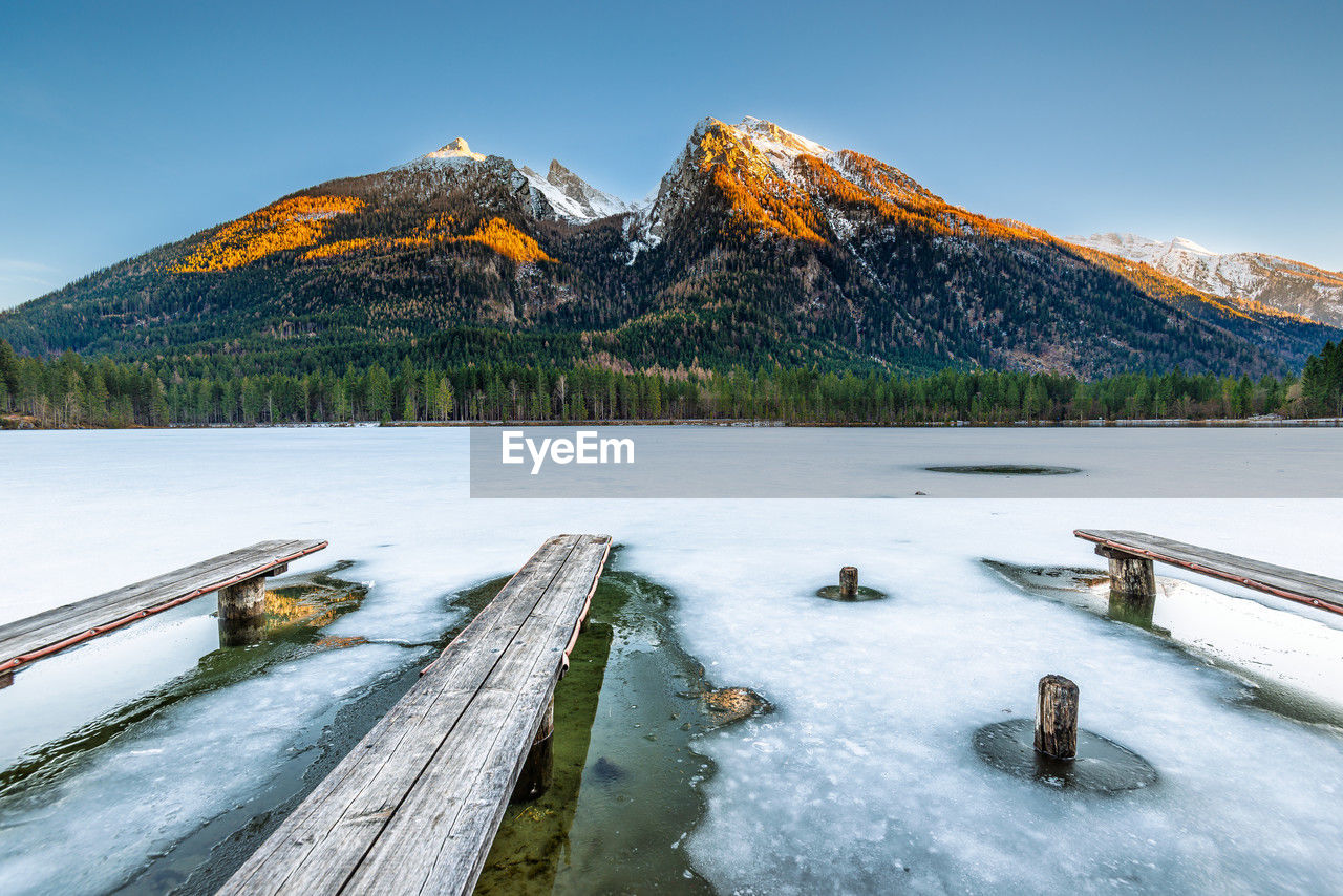 mountain, snow, scenics - nature, water, cold temperature, environment, winter, beauty in nature, landscape, reflection, nature, sky, lake, mountain range, land, wilderness, tree, no people, wood, travel destinations, tranquil scene, tranquility, plant, snowcapped mountain, travel, forest, mountain peak, outdoors, non-urban scene, day, blue, ice, frozen