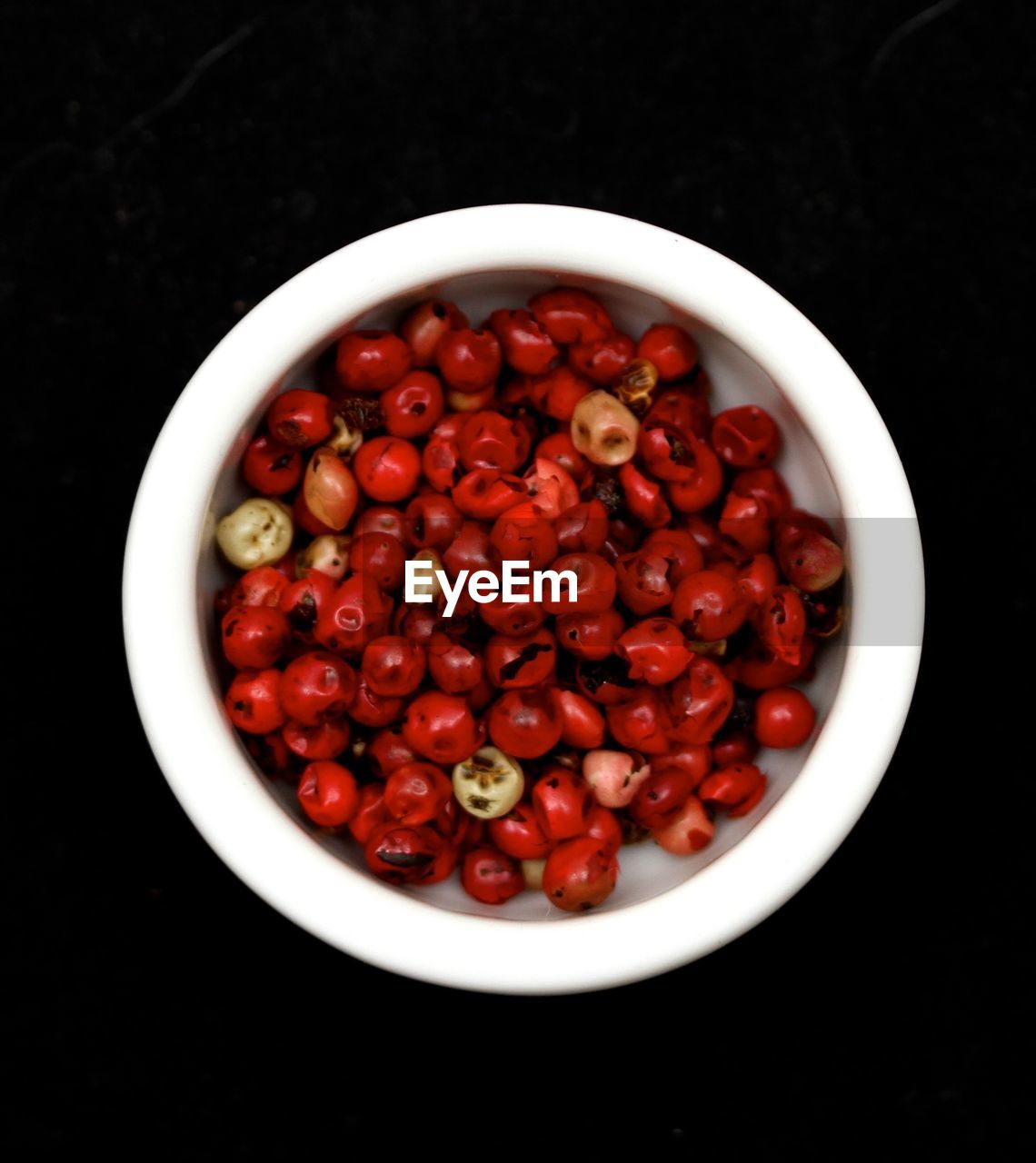 Directly above shot of red berries in bowl against black background