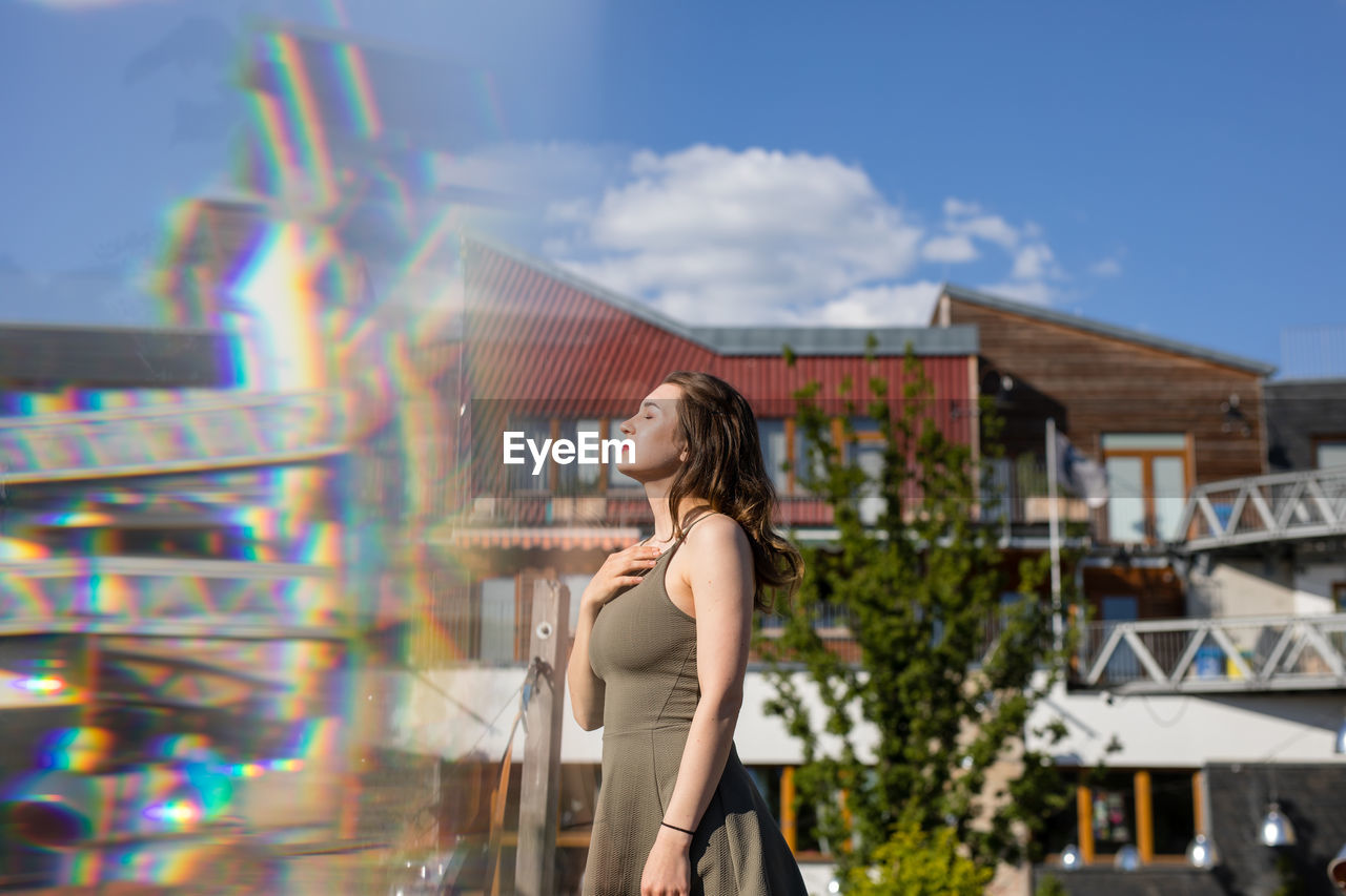 Double exposure of young woman and buildings during sunny day