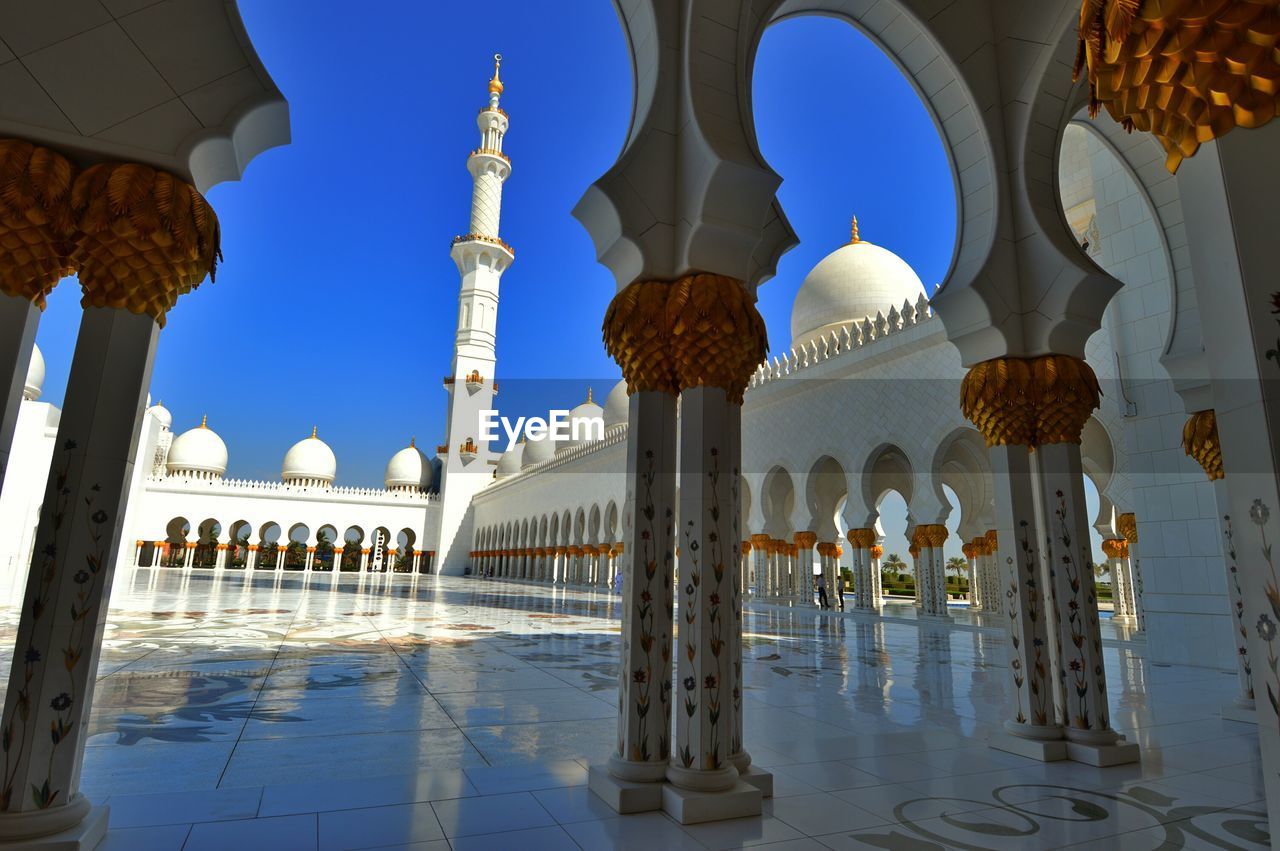 White and gold islamic architecture with colonnade and domes and minaret