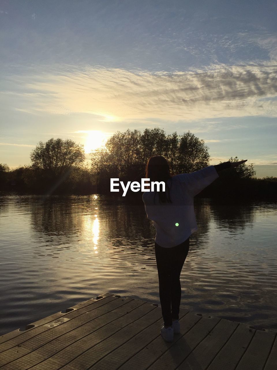 Woman on lake jetty at sunset