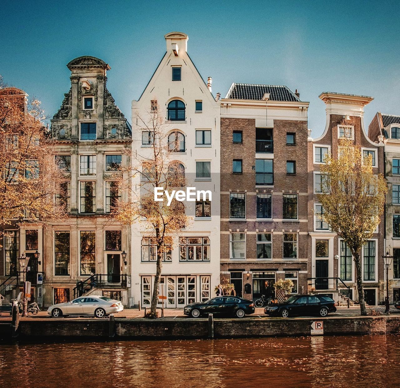 Buildings by canal against sky in city