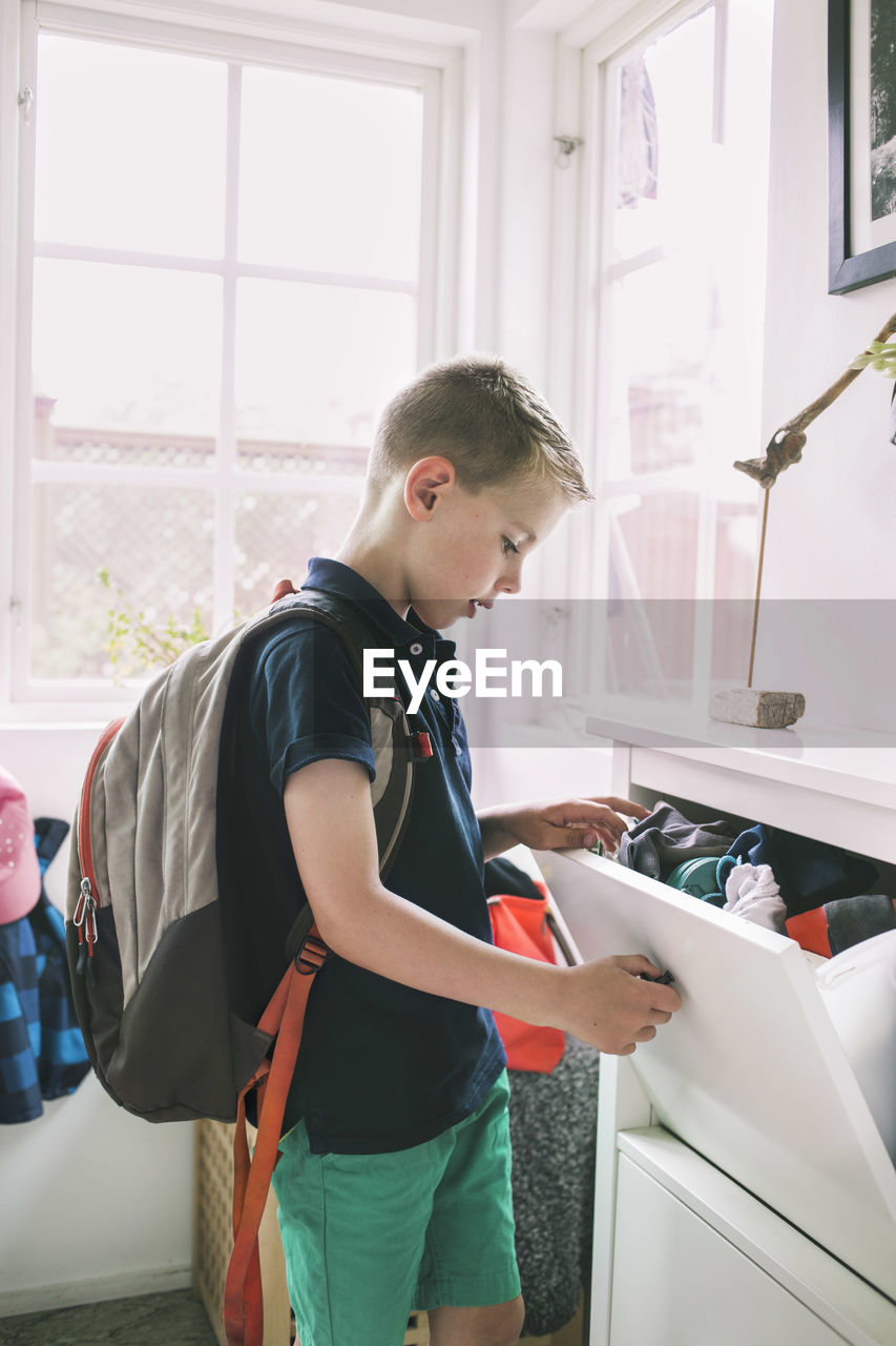 School boy searching for clothes in drawer at home