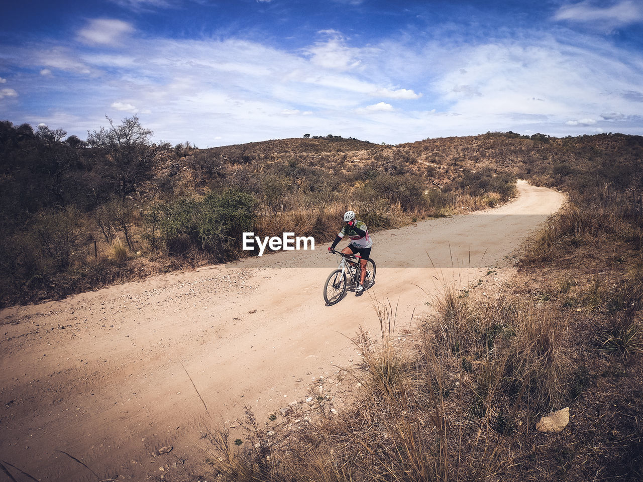 REAR VIEW OF MAN RIDING BICYCLE ON ROAD