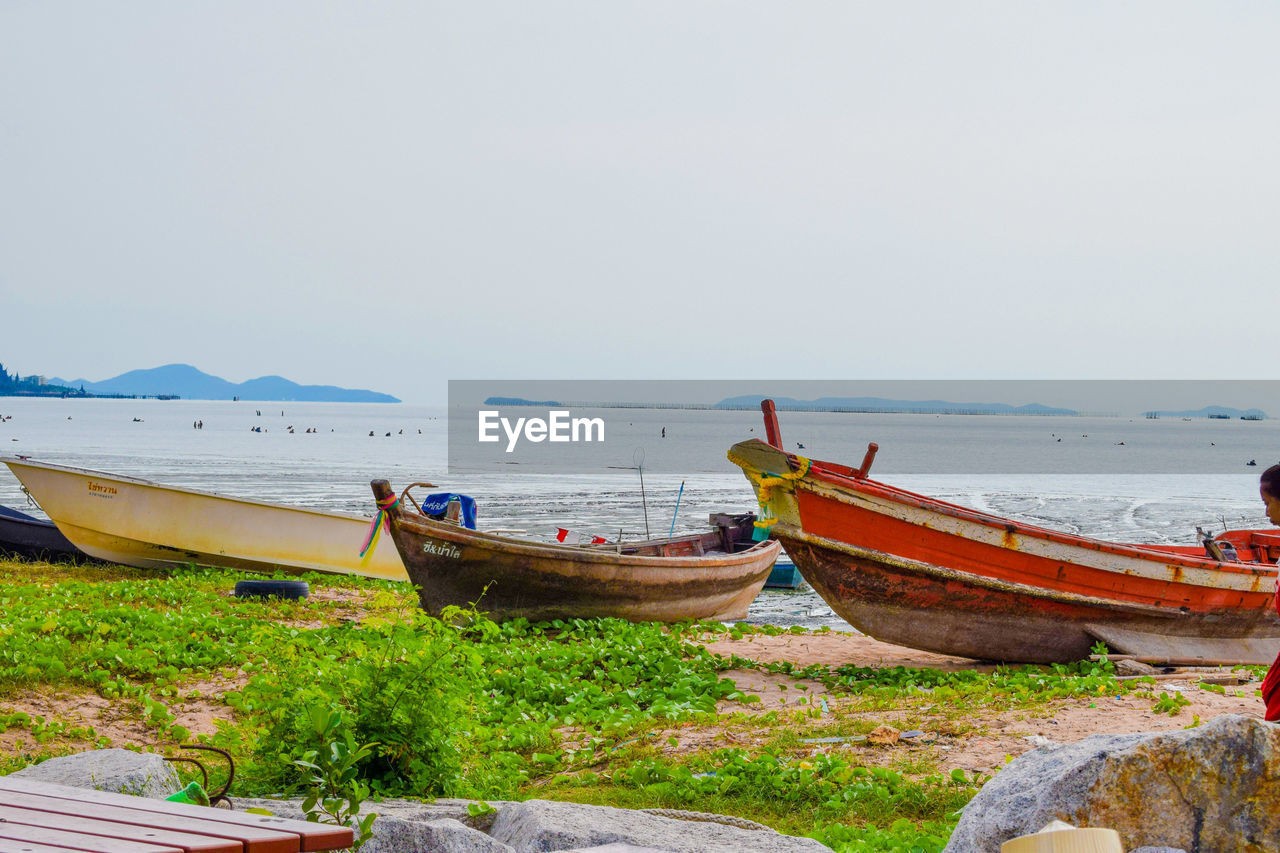 Boats moored on beach against clear sky