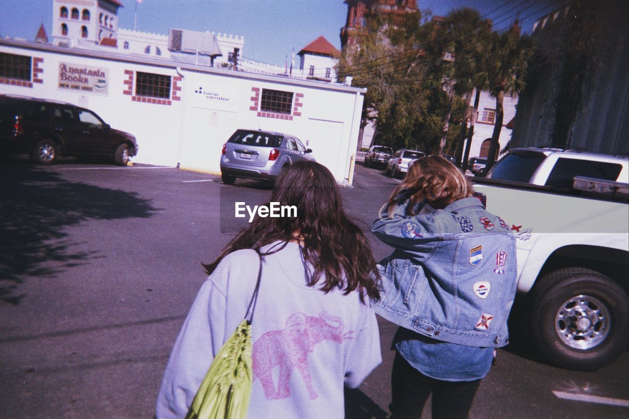 Rear view of girls standing on road against clear sky