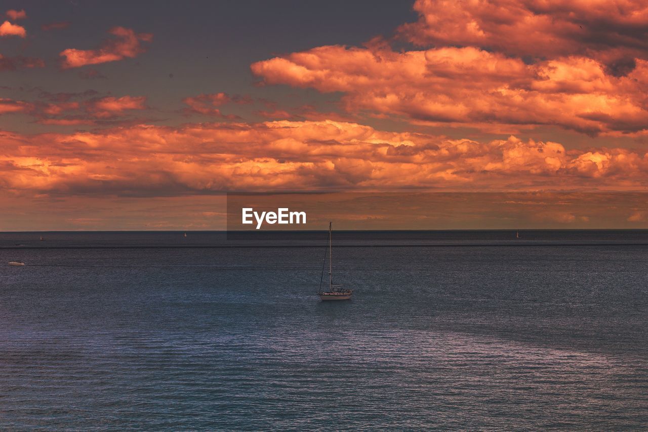 Scenic view of sea against cloudy sky at sunset