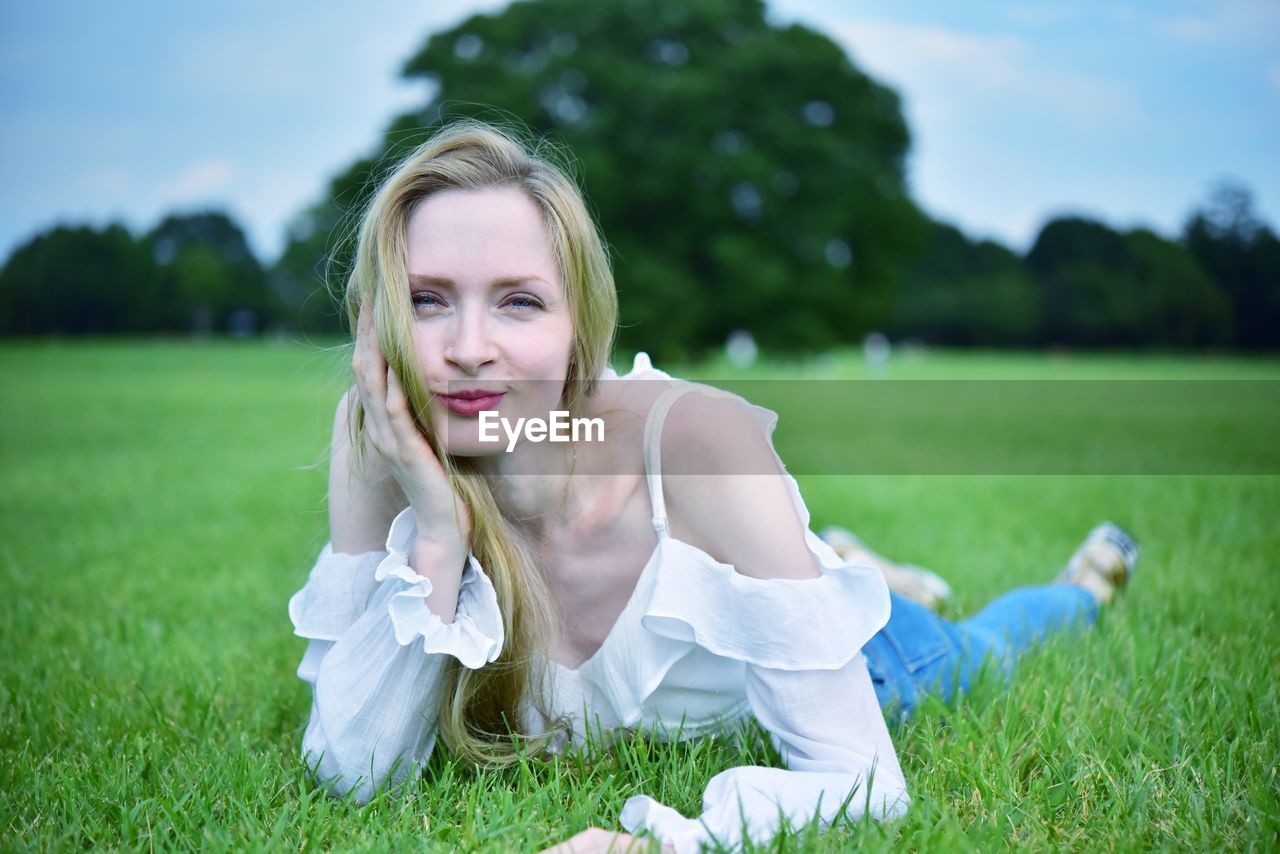 Portrait of young woman on grass in field