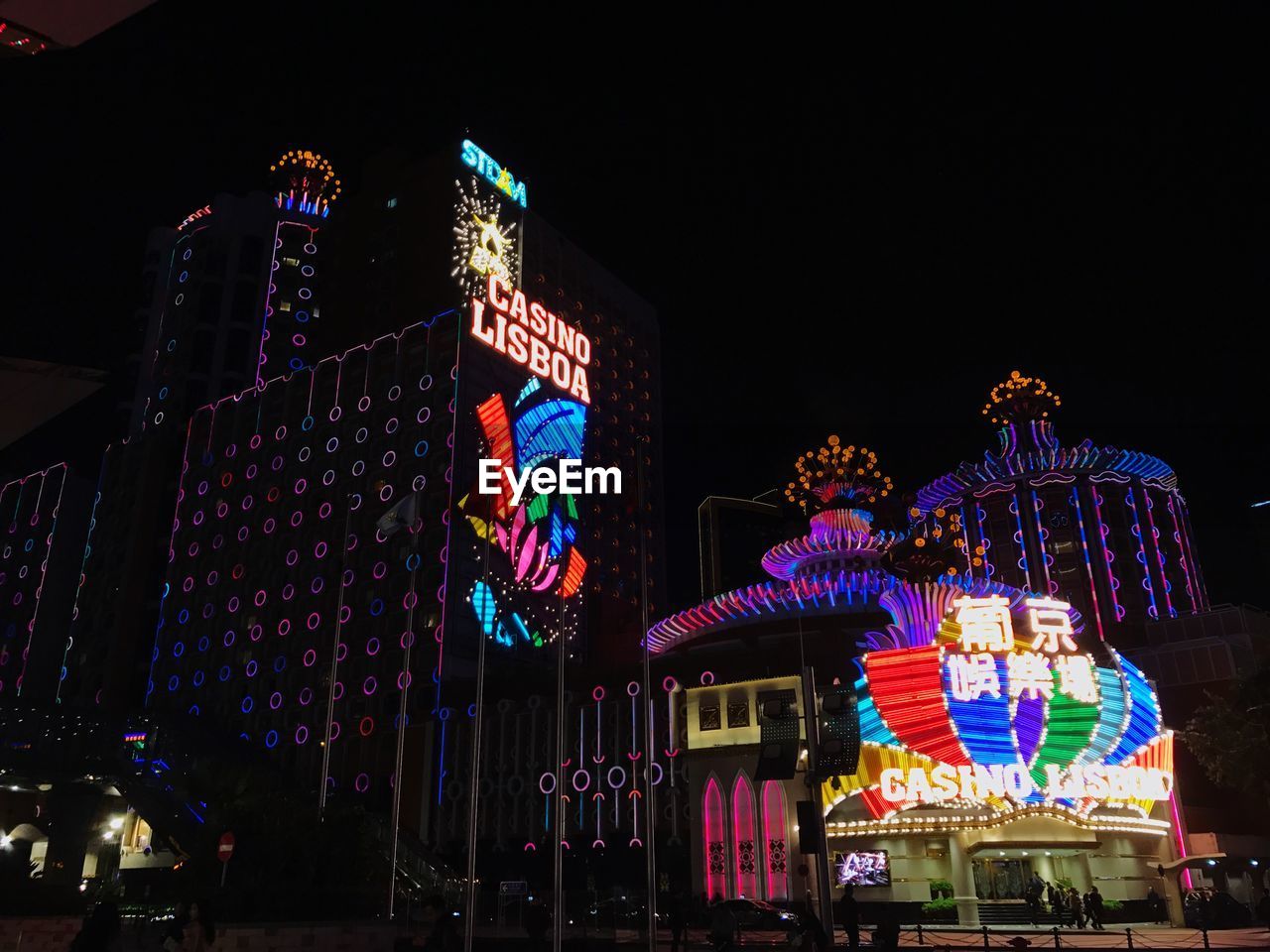 LOW ANGLE VIEW OF ILLUMINATED AMUSEMENT PARK AT NIGHT