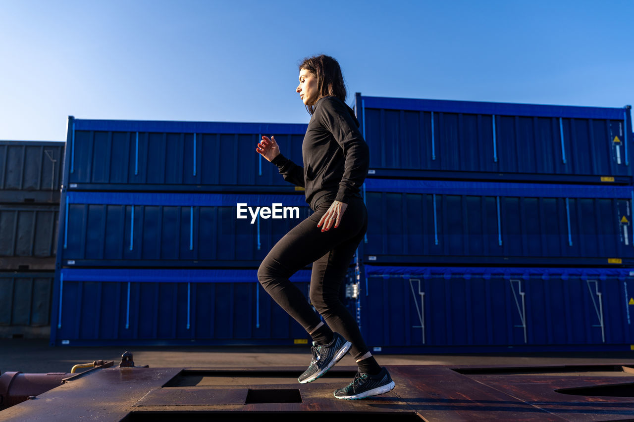 Side view of woman jogging against sky