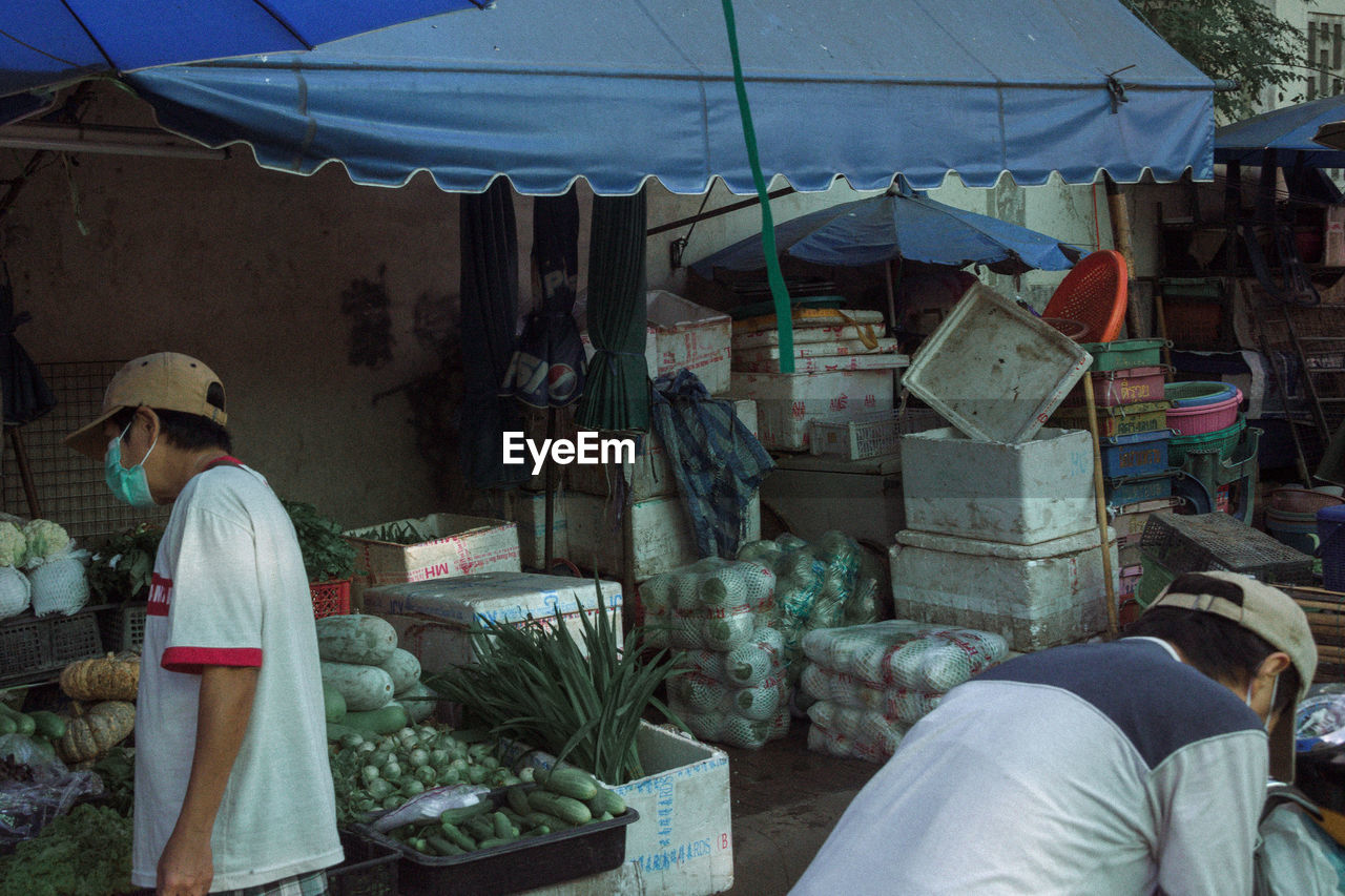 MIDSECTION OF WOMAN STANDING BY MARKET STALL