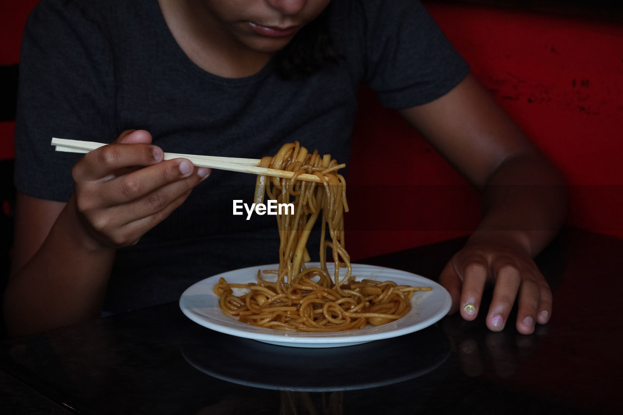 Midsection of woman eating noodles 