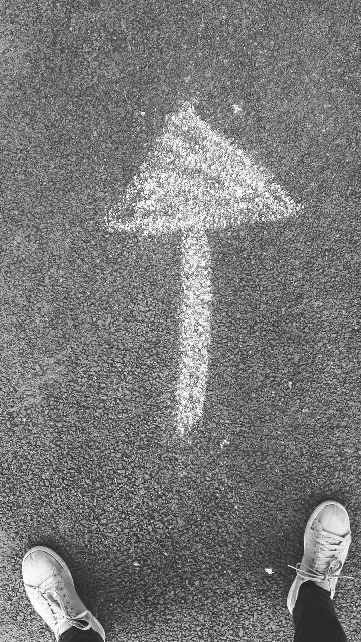 Person standing next to an arrow on the road