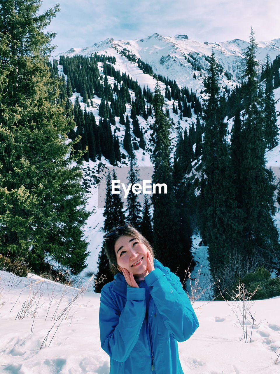 Portrait of smiling woman standing on snow covered mountain