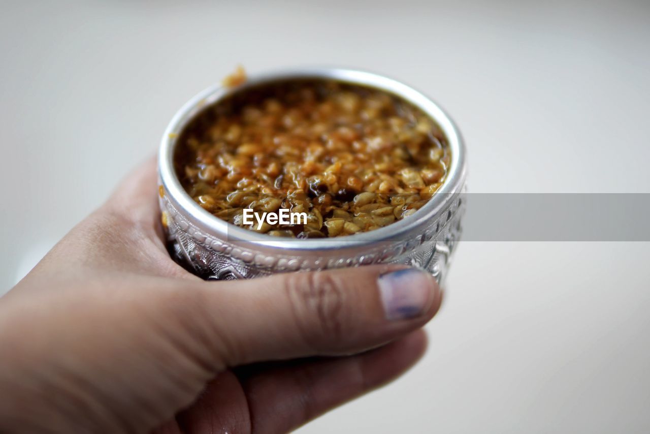 Midsection of woman holding food in bowl against white background