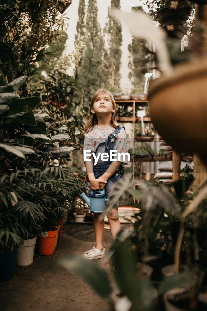 HAPPY GIRL STANDING AGAINST PLANTS