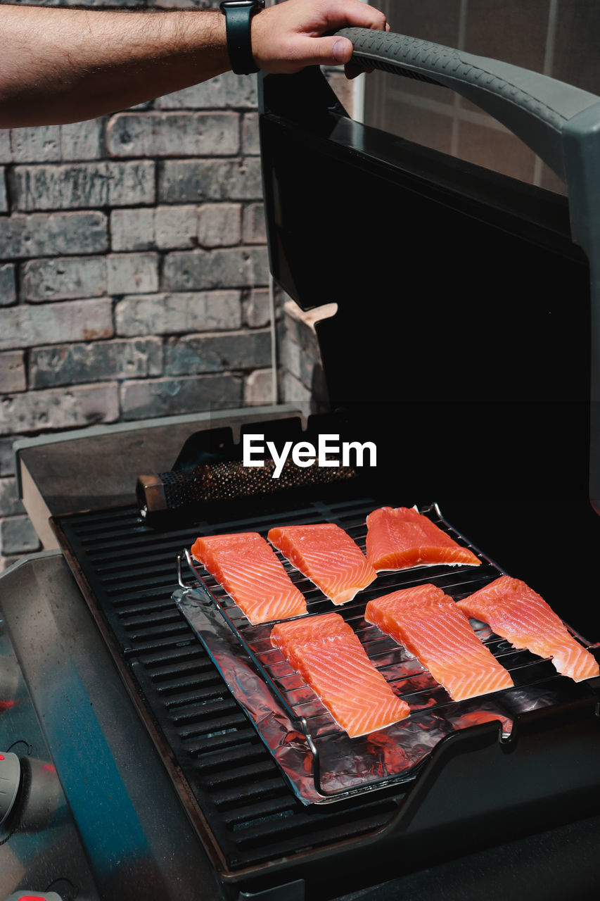 cropped hand of person preparing food on barbecue