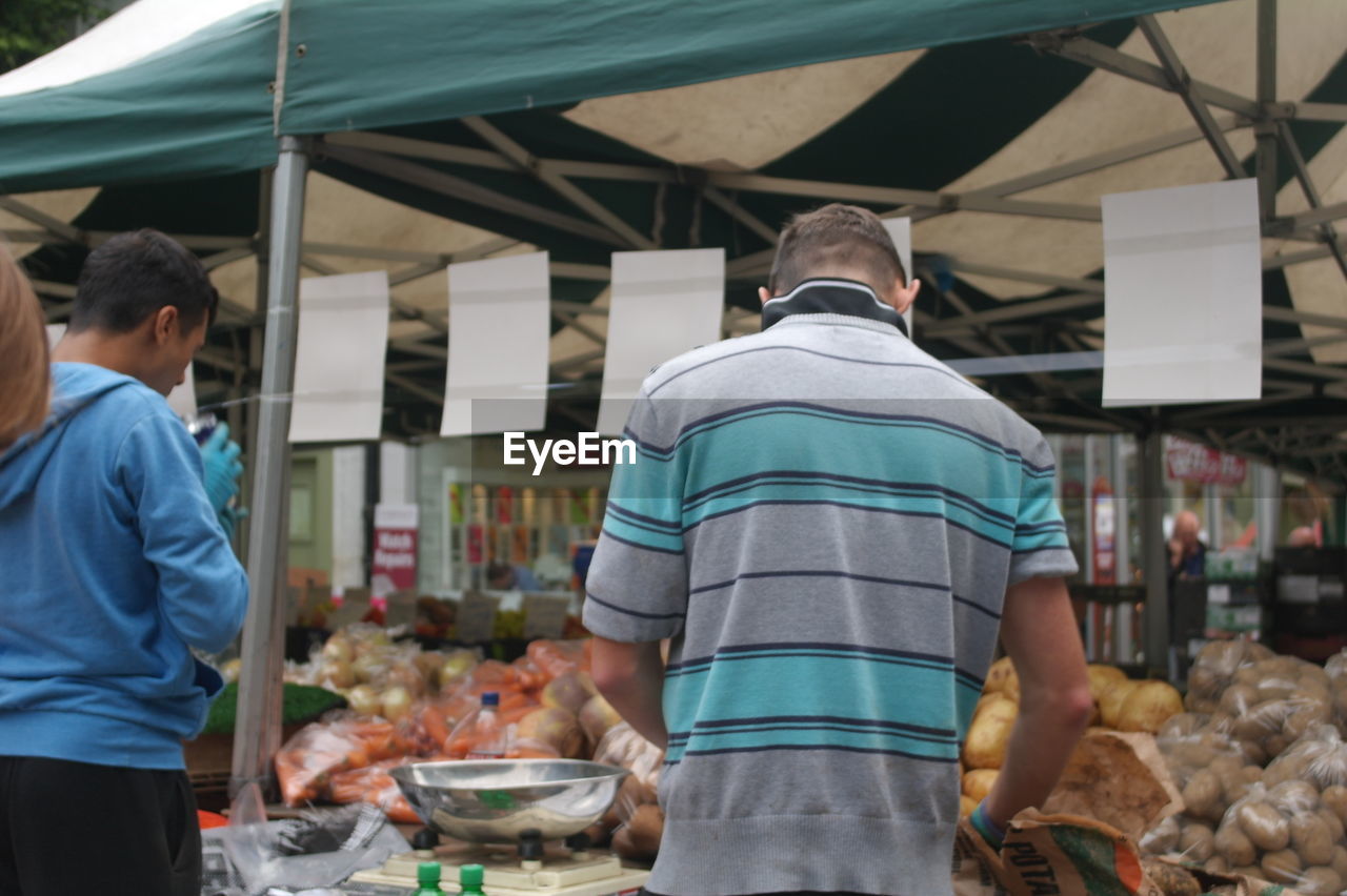 MAN AND WOMAN STANDING IN MARKET STALL