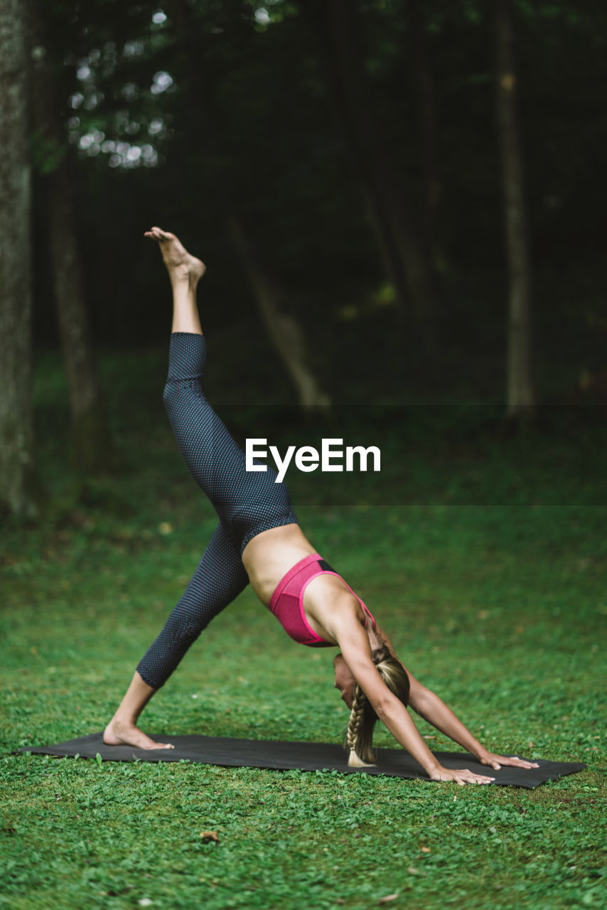 Full length of young woman exercising on field