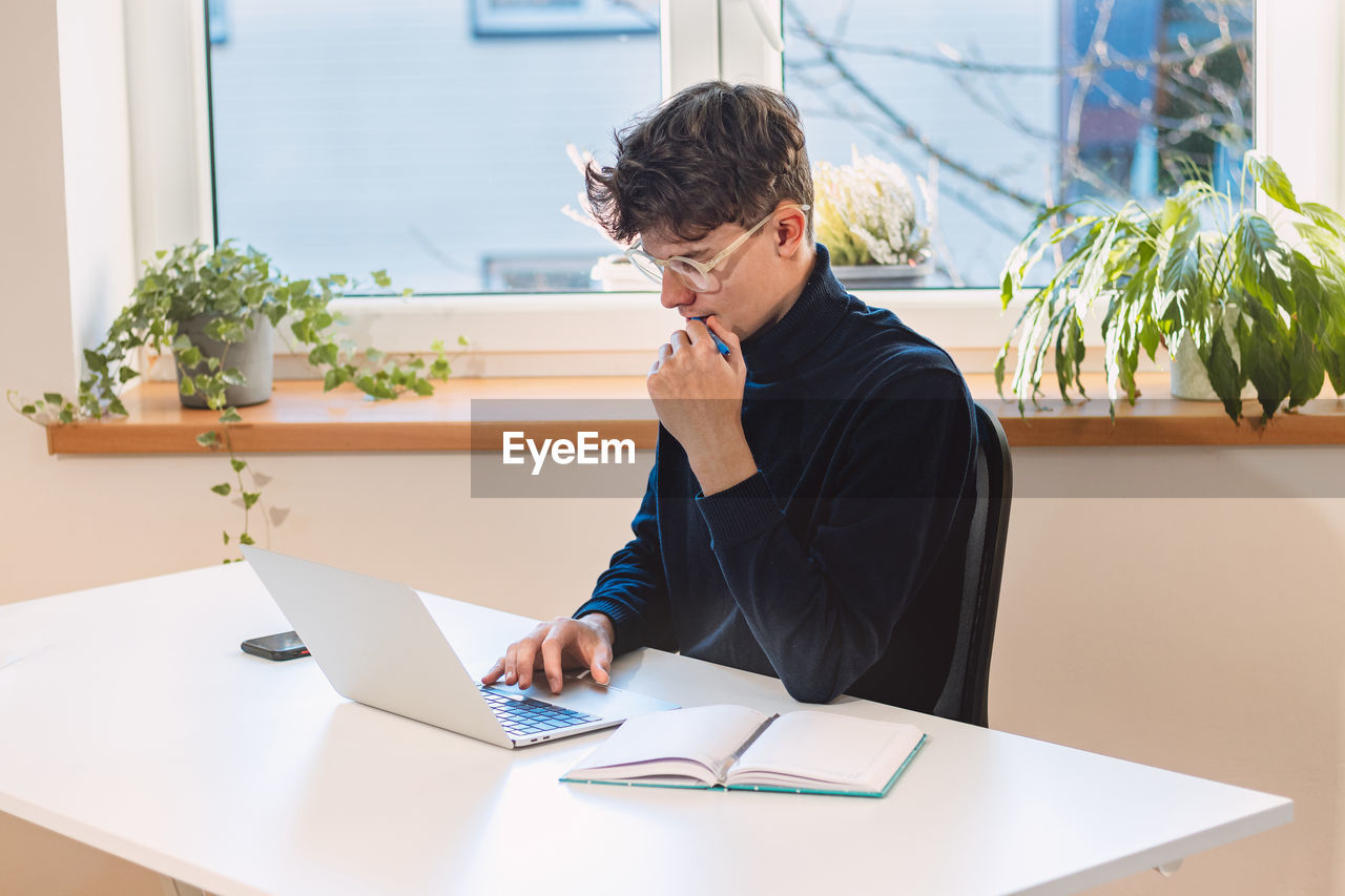 Entrepreneur in his study by the window is thinking of a new concept and strategy 