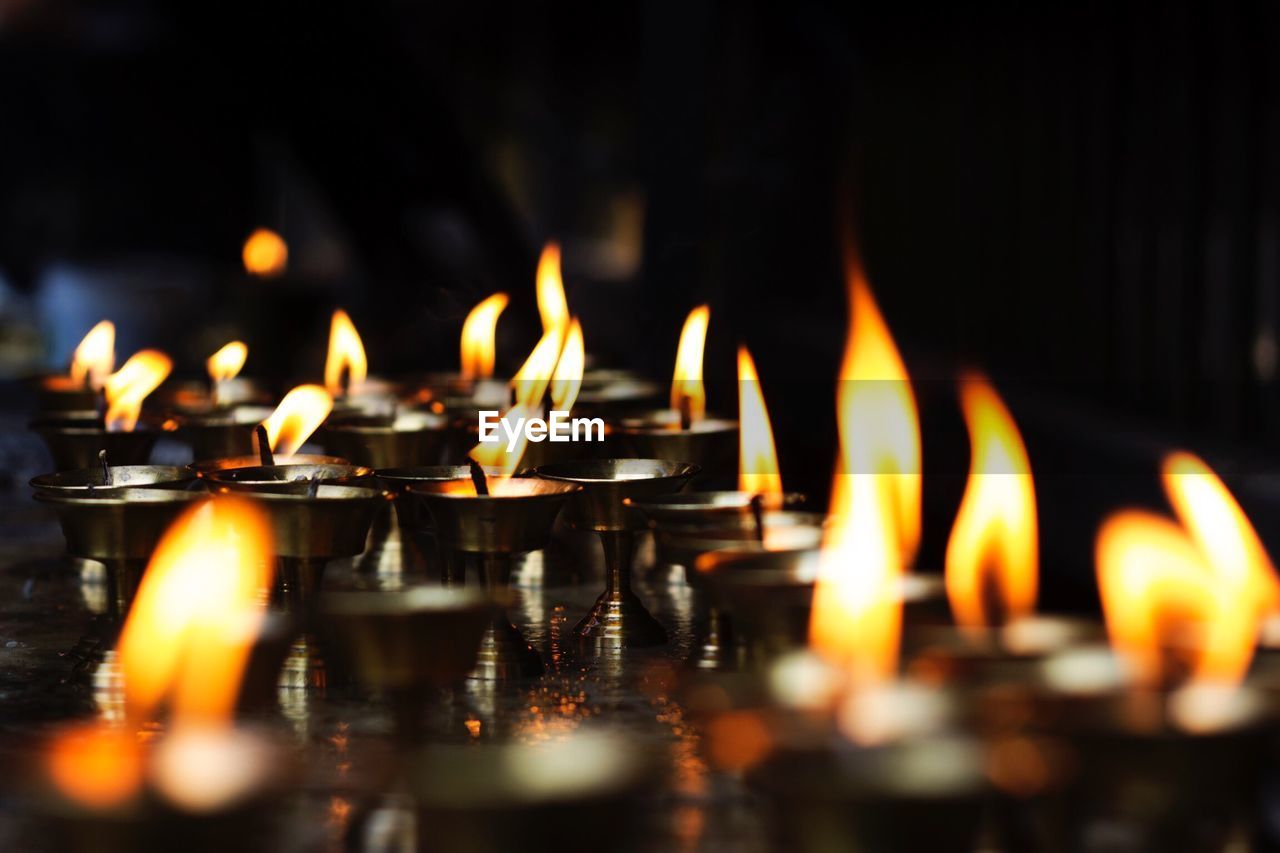 Close-up of burning diyas in temple