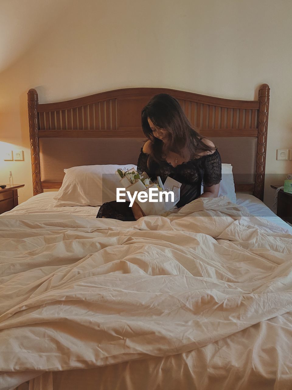WOMAN SITTING ON BED IN BEDROOM