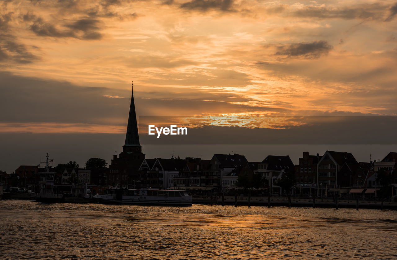 View of buildings by sea against sky during sunset