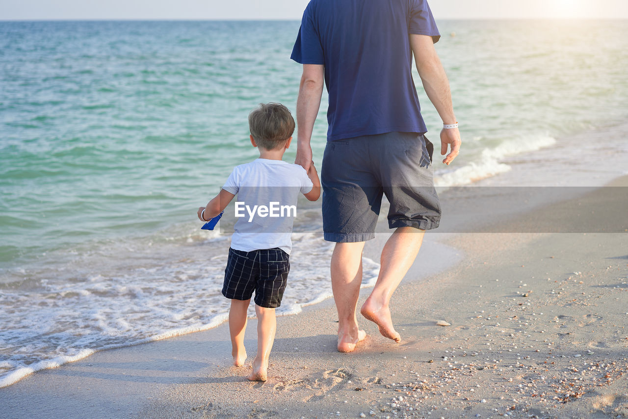 Rear view of father and son on beach