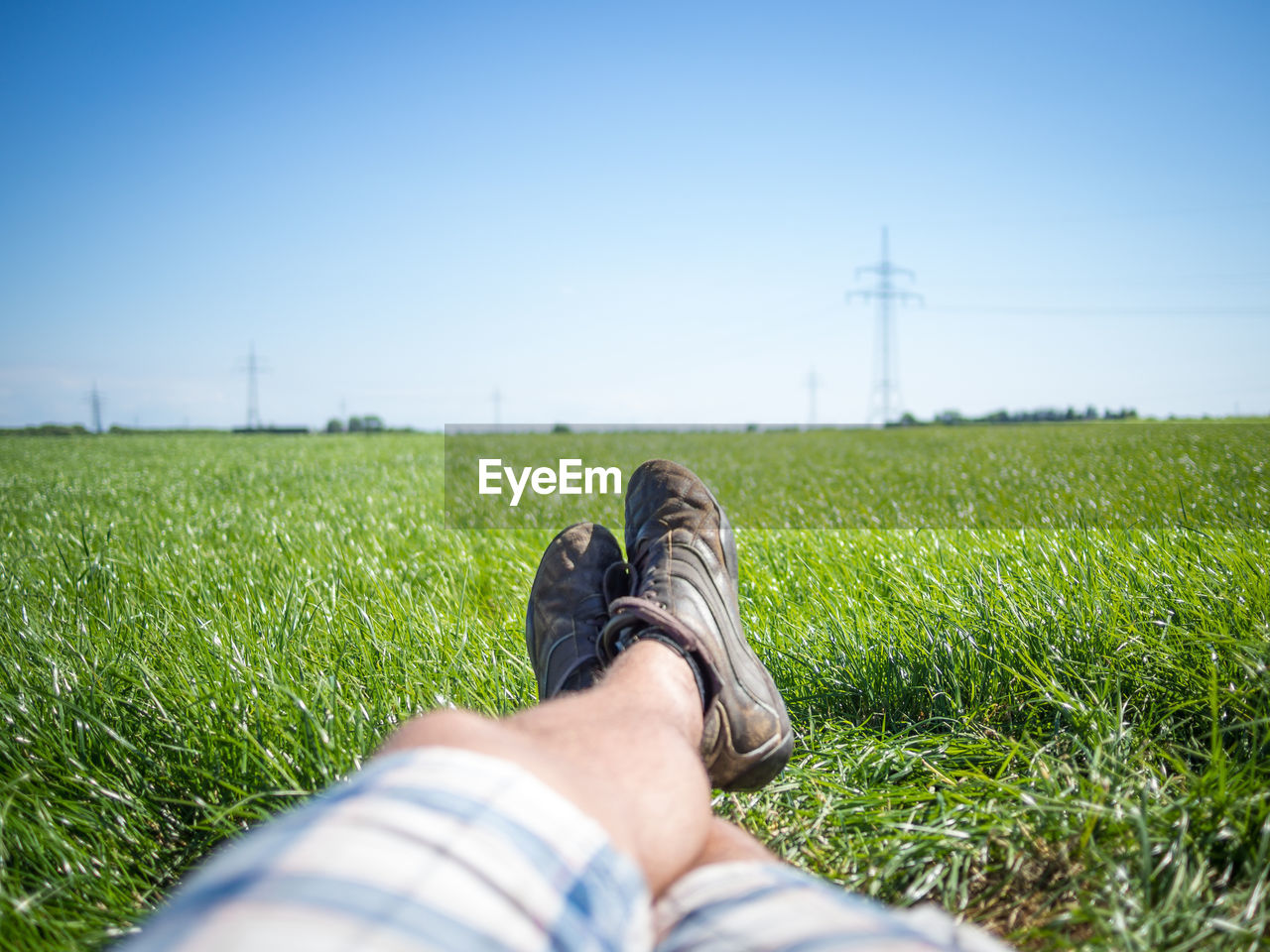 Low section of man lying on field against clear sky