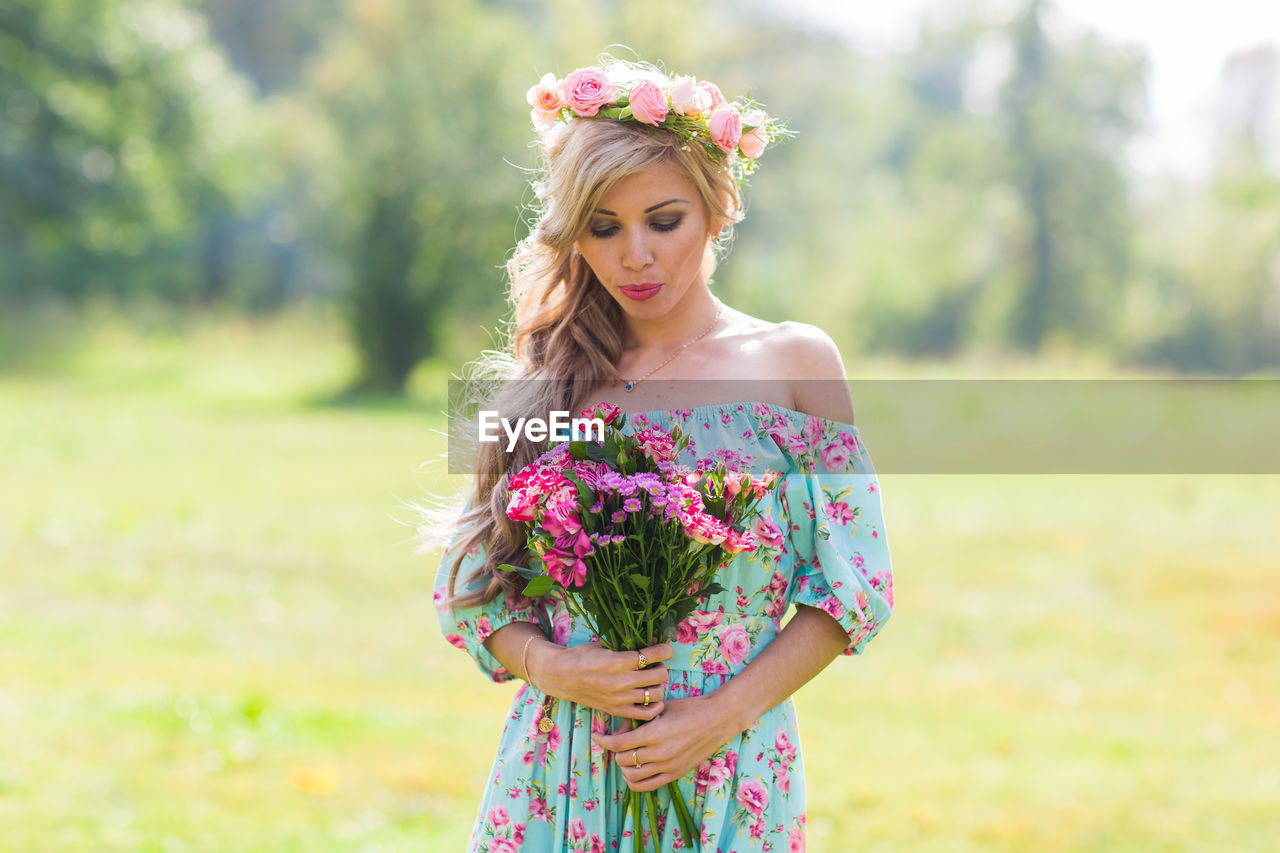 Young woman with pink flower standing against blurred background