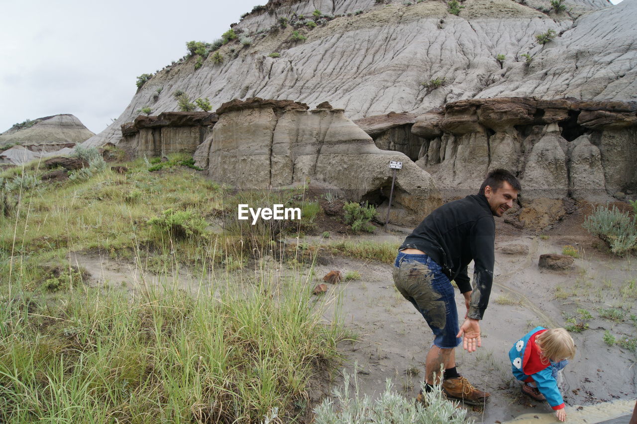 Full length of man standing with daughter by rock formation