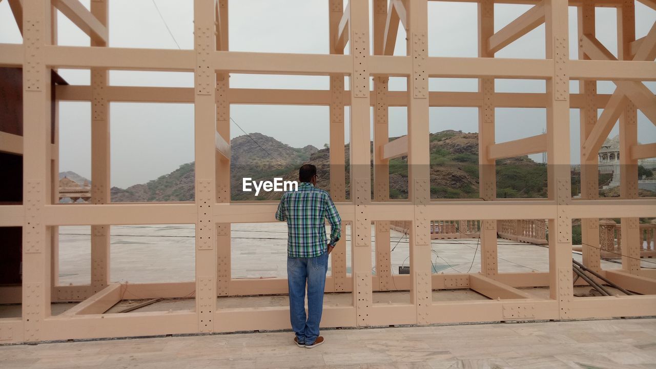 Rear view of man standing against built structure