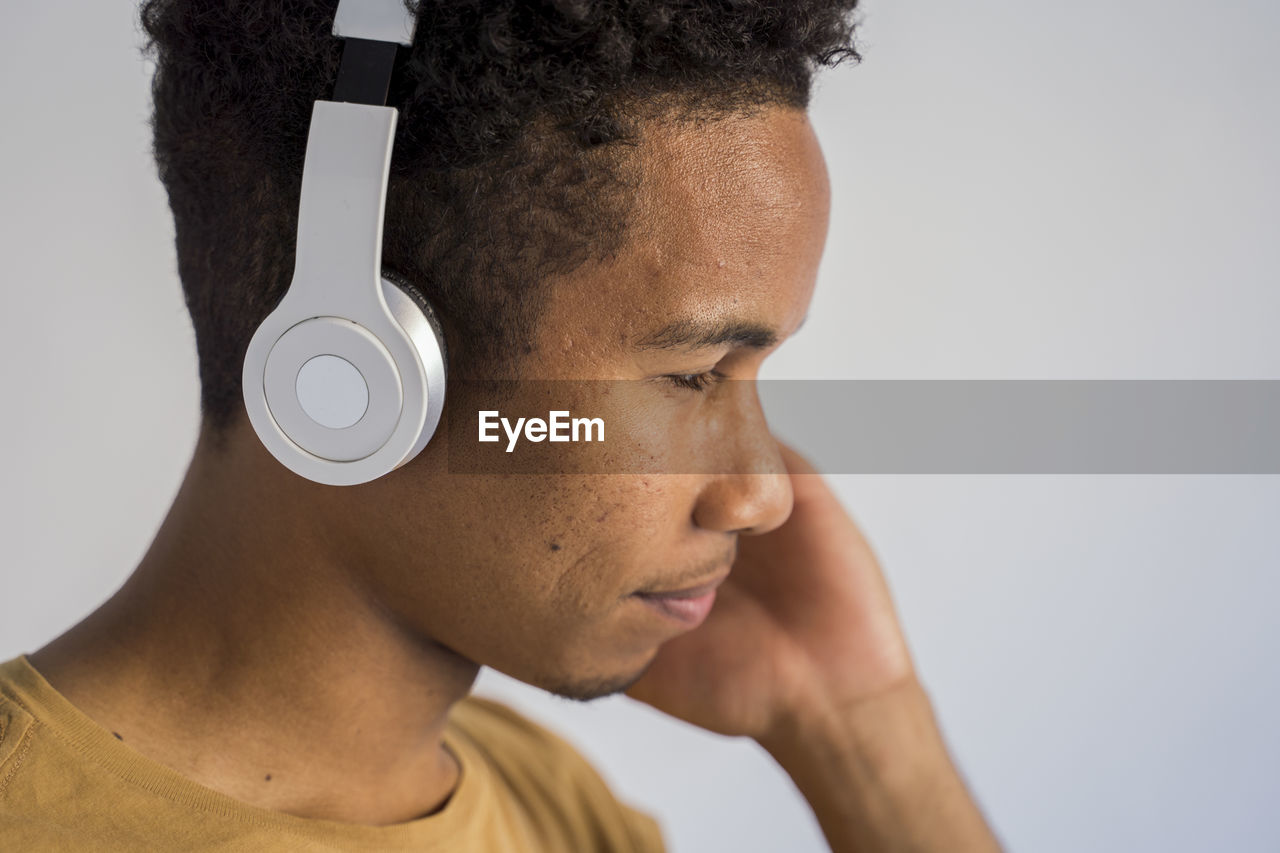 Close-up of man with headphone against white background