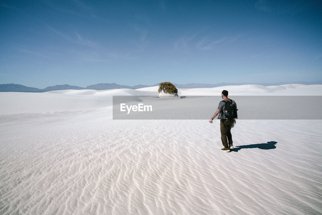 Full length of man walking on sand against sky