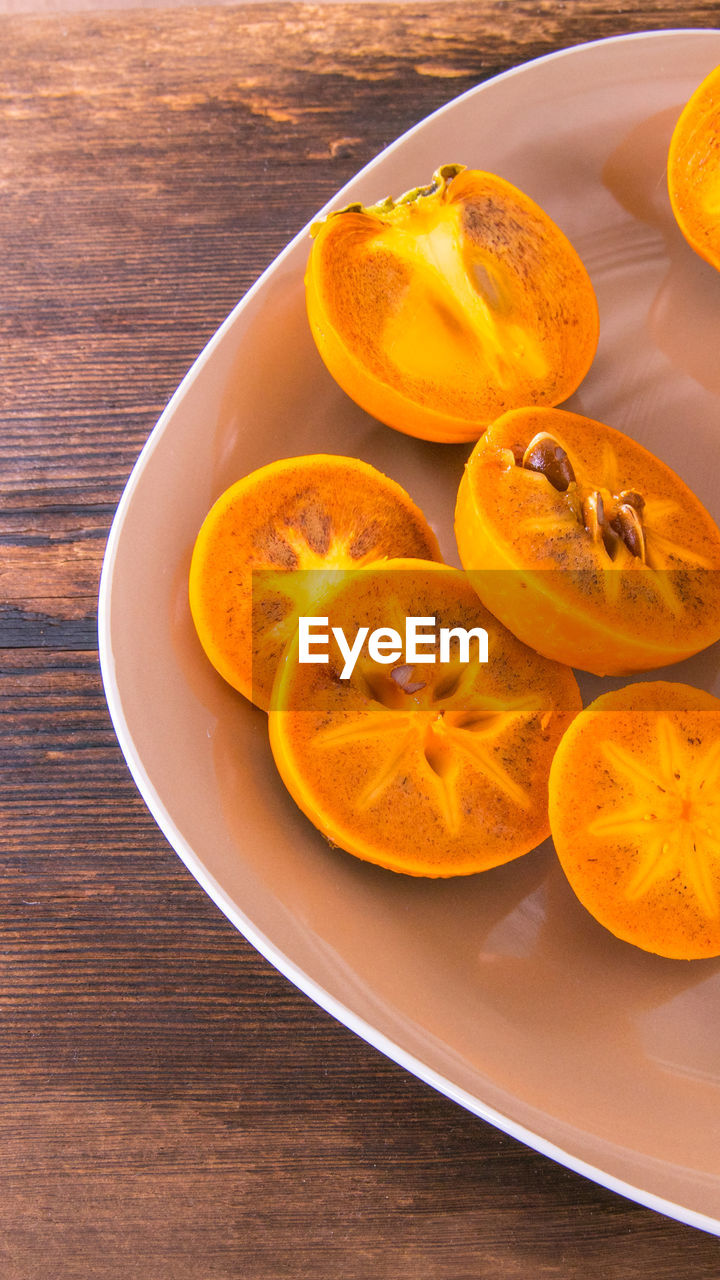 Persimmon cut into halves on a plate on a wooden table,copy space,closeup