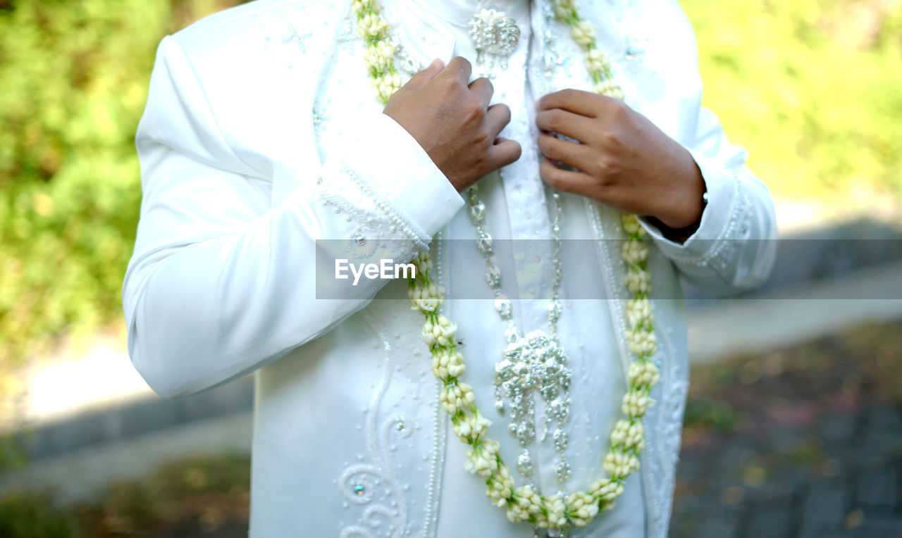 adult, bride, wedding, women, one person, newlywed, celebration, life events, event, nature, yellow, wedding dress, clothing, married, plant, day, jewelry, ceremony, midsection, love, hand, focus on foreground, holding, standing, emotion, traditional clothing, wedding ceremony, outdoors, white, positive emotion, flower, religion, young adult, lifestyles, female, sunlight, men, tradition, ring, belief, person, close-up